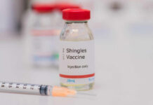 Vial of shingles vaccine next to a syringe