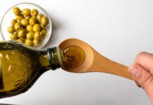 Pouring olive oil from a bottle into a wooden spoon