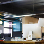 A modern office workspace featuring a computer, lamp, and decorative items on a desk