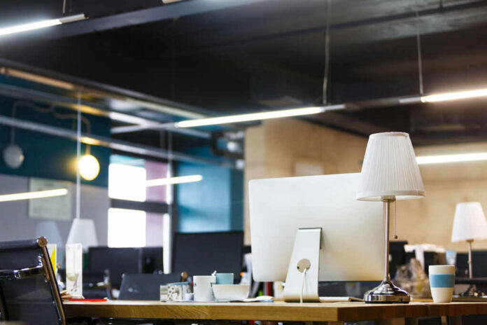 shutterstock_769869595.jpg A modern office workspace featuring a computer, lamp, and decorative items on a desk