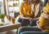 A couple and a friend discussing notes while seated in a cozy living room