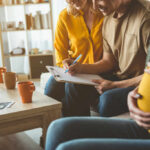 A couple and a friend discussing notes while seated in a cozy living room