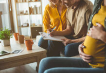 A couple and a friend discussing notes while seated in a cozy living room