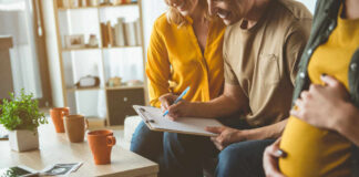 A couple and a friend discussing notes while seated in a cozy living room