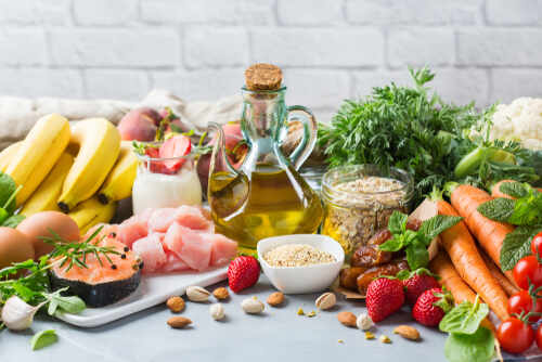 A variety of fresh foods including fruits, vegetables, and oils arranged on a table