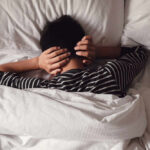 Night Owls Beware: Skin Damage Alert Child lying in bed with hands over ears