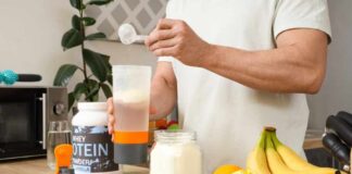 Person preparing a protein shake with fruits and whey protein powder in a kitchen