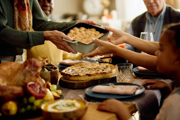 shutterstock_2372790555.jpg A family sharing a dish during a festive meal