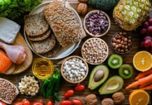 A variety of fresh foods including vegetables, fruits, grains, and proteins arranged on a wooden surface