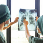 Cancer’s Secret Off Switch — Finally Found! Two medical professionals examining an x-ray of a chest