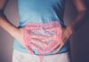 Travel Constipation: Treatments and Home Remedies to Try Person holding their stomach with a graphic of intestines overlayed