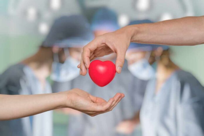 Two hands exchanging a red heart symbol in a surgical setting