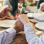 Couple holding hands over a dining table with food and drinks