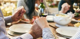 Couple holding hands over a dining table with food and drinks