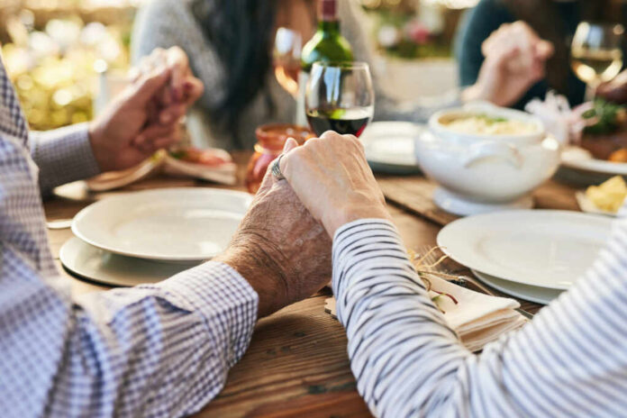 shutterstock2231974901jpg Couple holding hands over a dining table with food and drinks