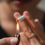 Cannabis Smoke, Tobacco-Level Danger? A close-up of a hand holding a cigarette being lit by a lighter