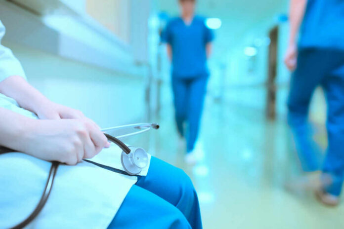 shutterstock402478774jpg A healthcare professional holding a stethoscope in a hospital corridor