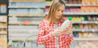 Woman reading a bottle label in a grocery store aisle