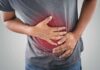 Person clutching stomach with colon illustration overlay