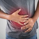Person clutching stomach with colon illustration overlay