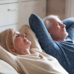 Two adults relaxing on a couch with eyes closed