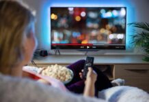 How long-term TV watching affects brain health in adults Person sitting on a couch watching a movie on a TV with popcorn in hand
