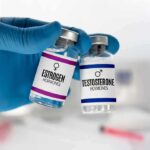 Gloved hand holding estrogen and testosterone vials