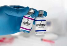 Gloved hand holding estrogen and testosterone vials