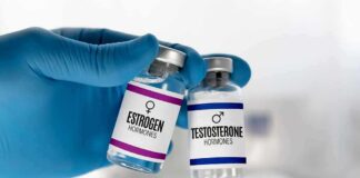 Gloved hand holding estrogen and testosterone vials