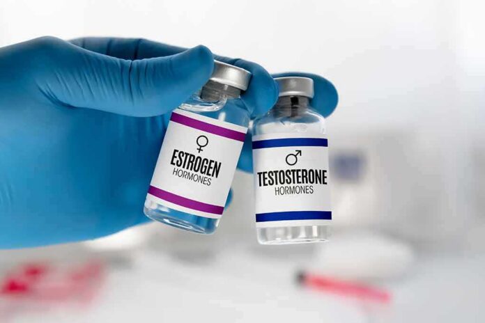 Gloved hand holding estrogen and testosterone vials