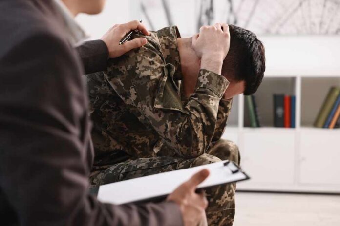 Soldier in camouflage sits with head in hands during counseling session