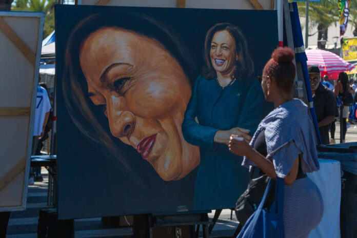 A woman admires a large portrait of a smiling female figure at an outdoor event