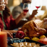 A beautifully roasted turkey surrounded by fruits and candles on a festive dining table