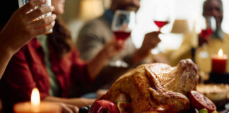 A beautifully roasted turkey surrounded by fruits and candles on a festive dining table