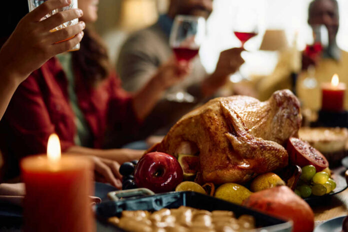 A beautifully roasted turkey surrounded by fruits and candles on a festive dining table