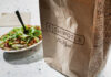 A Chipotle takeout bag next to a bowl filled with fresh salad ingredients