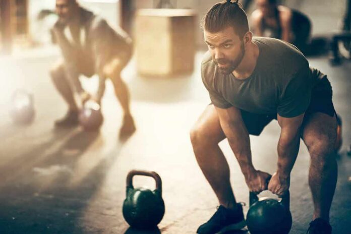 shutterstock_1043370892 Man lifting a kettlebell in a gym