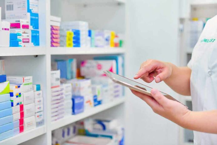 Pharmacist using a tablet in front of stocked pharmacy shelves