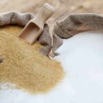 Brown and white sugar in burlap sacks with wooden scoop