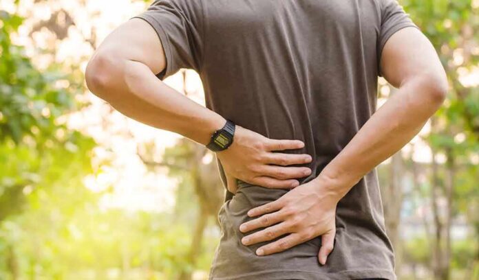 person holding lower back outdoors