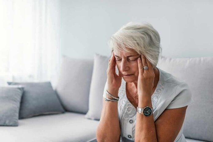 1783890225942-szj9d5-shutterstock-1129274345 Older woman sitting on a couch holding her temples