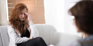 Woman with hand on forehead sitting on couch during therapy session