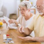 Doctor Favorite BP Drug Linked To Kidney Collapse Older man taking pills at a table while woman reads instructions