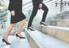 Two businesspeople in formal wear walking up stairs
