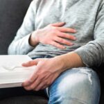Cancer Flags Ignored in Everyday Food Packaging Person holding takeout container while touching stomach