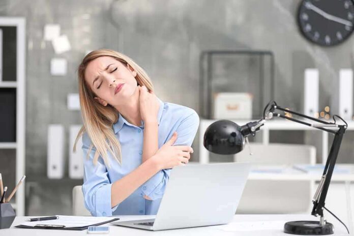 Woman at desk massaging her neck in discomfort