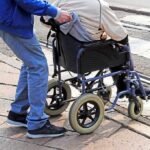 Caregiving Health Risks: When Helping Turns Hazardous Caregiver pushing person in wheelchair over curb