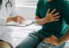 Patient holding chest while doctor takes notes