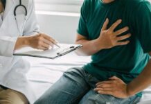 Patient holding chest while doctor takes notes