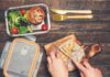 Hands slicing cooked chicken on a wooden cutting board